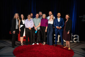 The speakers of TEDxKanata gather on stage alongside their coaches and organizers of the event. 