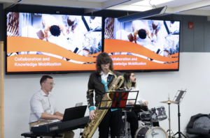 Students from Carleton University's music program perform as a jazz trio with piano, saxophone, and drums.